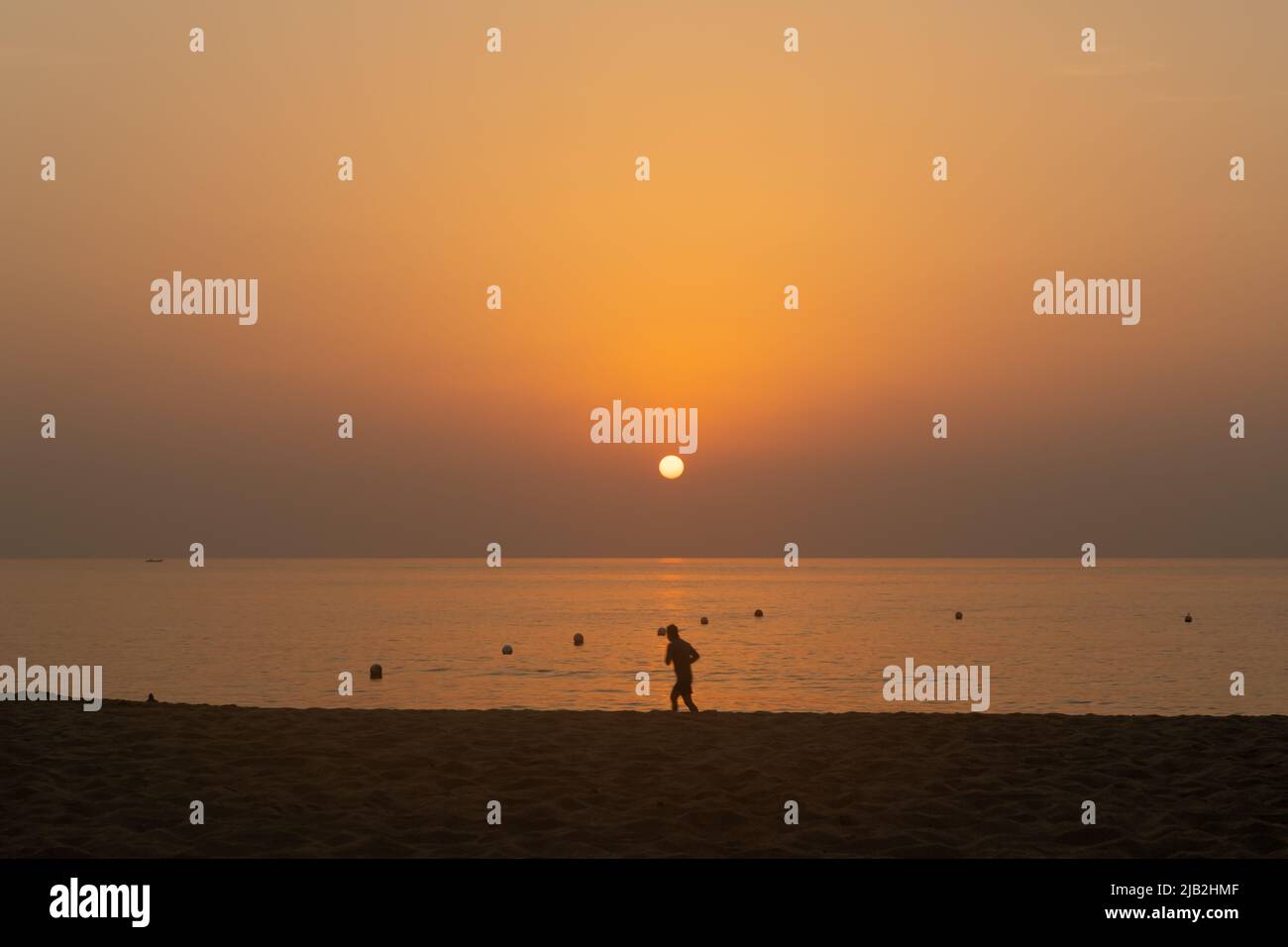 Silhouette di un pareggiatore solita che si esercita su una spiaggia vuota durante l'alba. Fitness e stile di vita sano concetto. Foto Stock