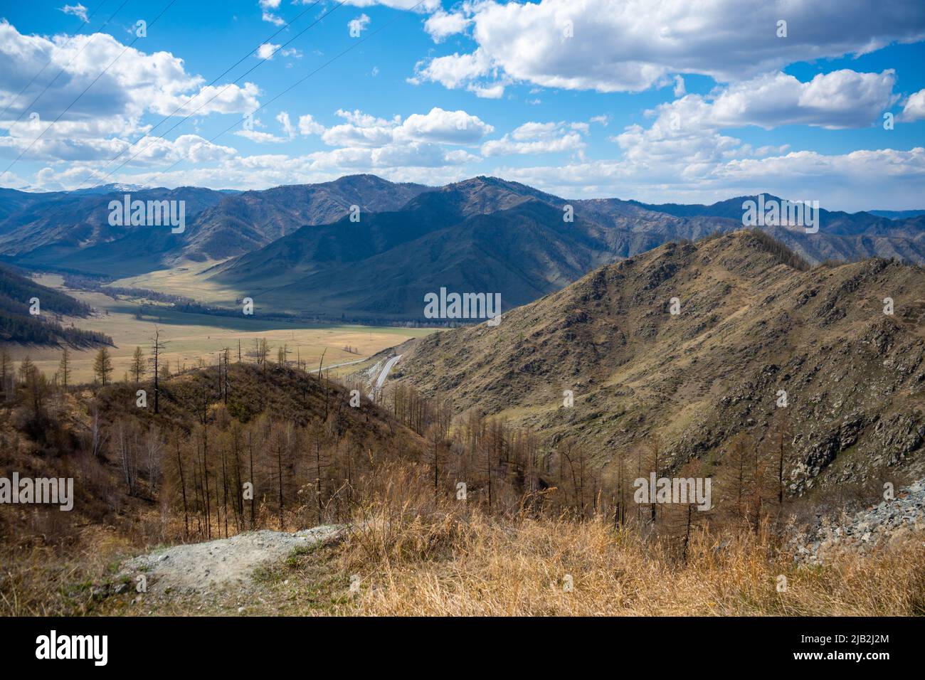 Vista panoramica dal passo di montagna alla valle della foresta tra catene montuose e colline all'orizzonte con tempo variabile in primavera ad Altai, Russia Foto Stock