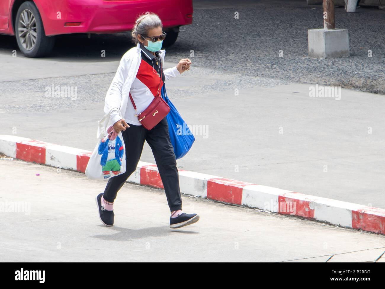SAMUT PRAKAN, THAILANDIA, MAGGIO 06 2022, donna anziana con borse che corrono lungo la strada Foto Stock