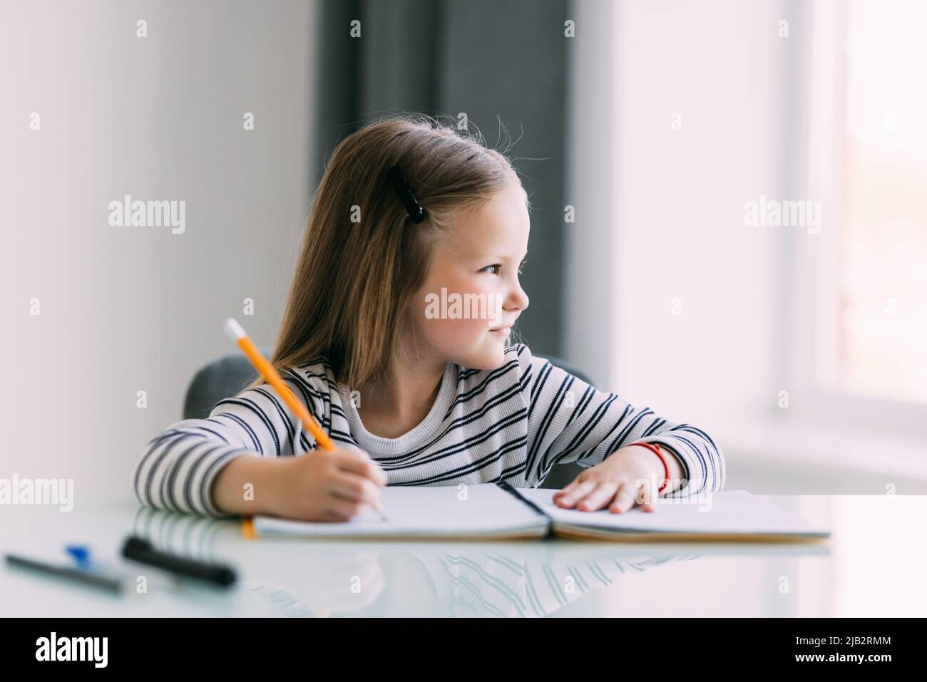 Carino bambina facendo i compiti, la lettura di un libro, pagine da colorare, Scrittura e pittura. I bambini la vernice. Bambini disegnare. Foto Stock