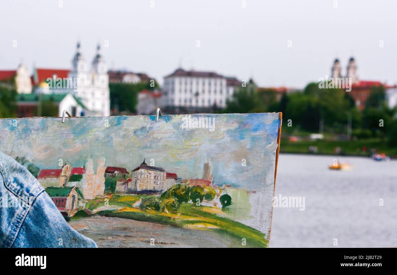 Minsk, Bielorussia - 05 maggio 2014: Un artista della città dipinge un paesaggio urbano. Parte della tela e la vista di che cosa disegna. Foto Stock