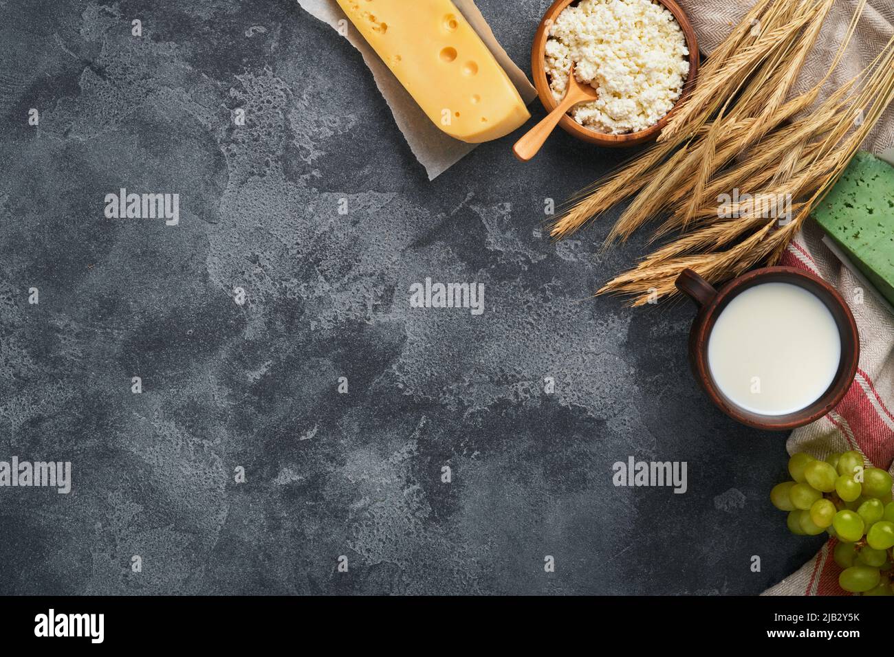 Felice Shavuot. Sfondo per la tradizionale celebrazione religiosa ebraica Shavuot. Latte e formaggio, grano maturo e frutta. Latticini sopra vecchio g scuro Foto Stock