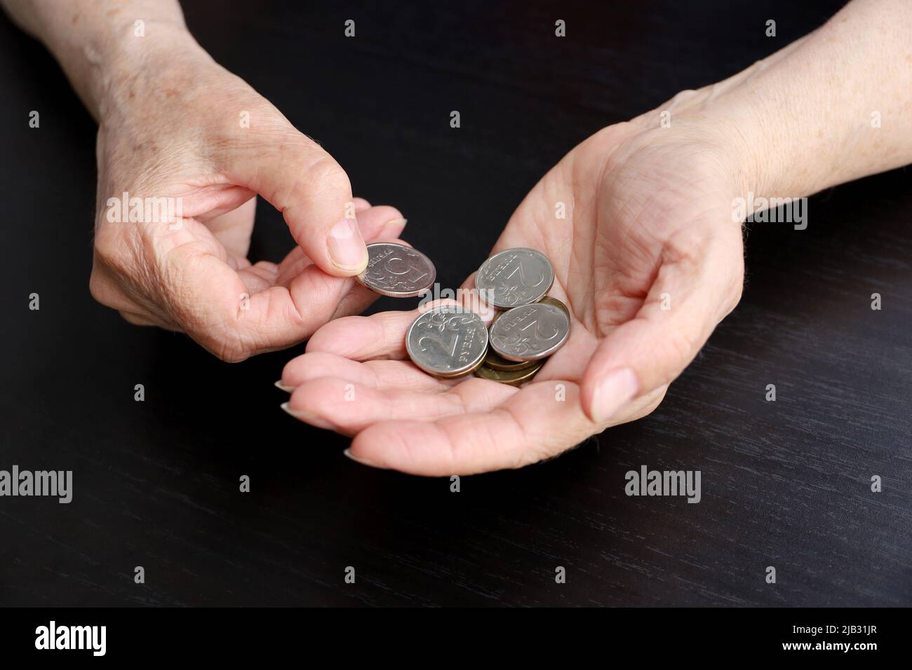La donna anziana conta rubli russi in monete, le mani femminili rugose in primo piano. Concetto di povertà in Russia, pagamenti pensionistici Foto Stock