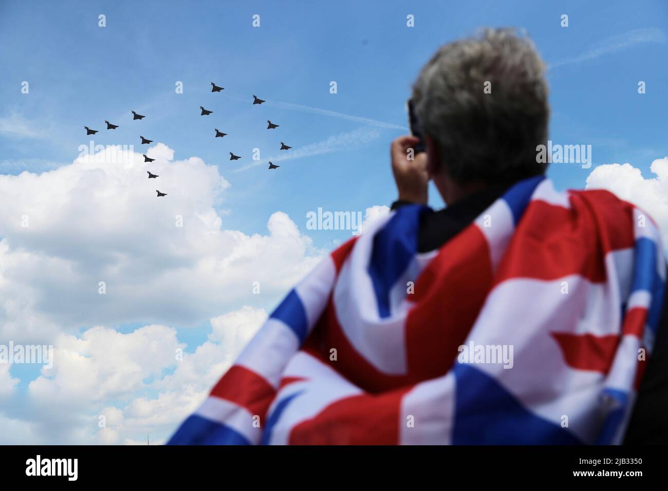 Londra, Regno Unito. 2nd giugno 2022. Un uomo che indossa una bandiera Union Jack scatta foto dei jet Fighter della RAF britannica (Royal Air Force) Vola in formazione per formare il numero '70' durante uno speciale passatappi sulla città di Londra durante le celebrazioni del Giubileo del platino della regina Elisabetta britannica per celebrare il 70th anniversario della sua adesione al trono il 6 febbraio 1952, a Londra. (Credit Image: © May James/SOPA Images via ZUMA Press Wire) Foto Stock