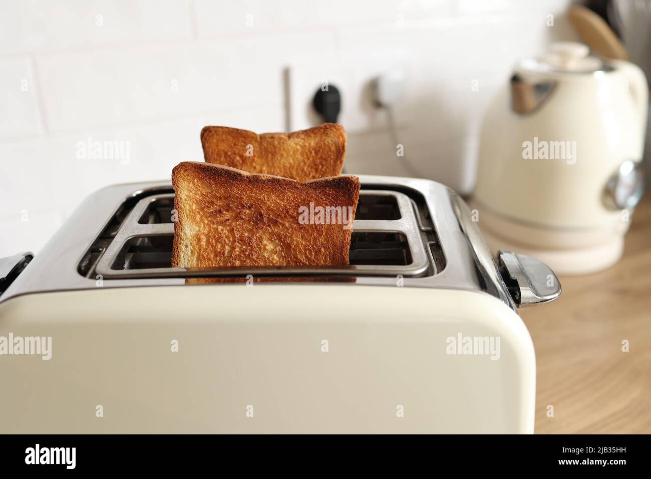 Moderno tostapane bianco e fette di pane tostate si tostano all'interno su  un tavolo di legno in cucina Foto stock - Alamy