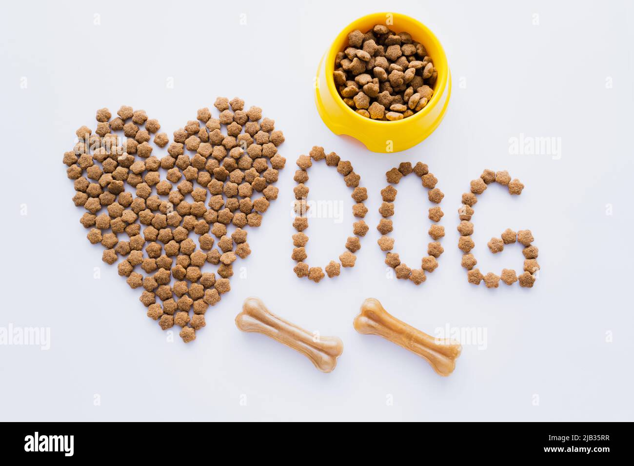 vista dall'alto degli alimenti secchi per animali domestici a forma di cuore vicino alle lettere del cane e alle ossa isolate su bianco Foto Stock