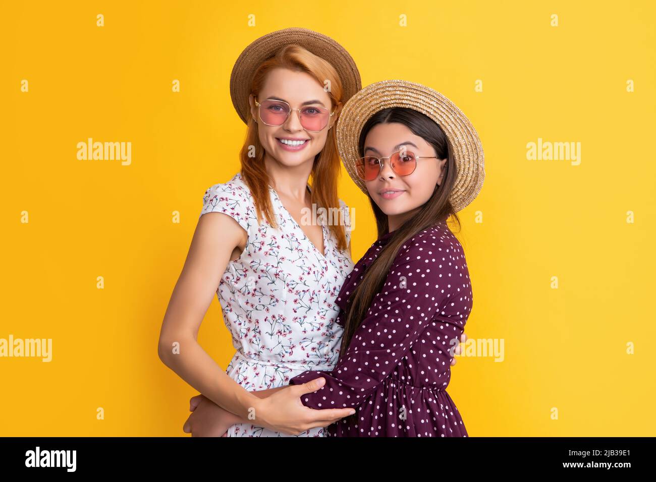 madre e bambino sorridenti in cappello di paglia su sfondo giallo Foto Stock