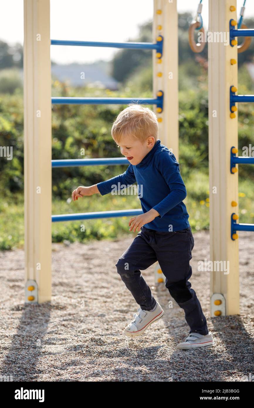 Il ragazzino inizia a correre all'aperto in un parco giochi in una giornata estiva. Il concetto di sport per bambini e attivo in aria fresca. Foto Stock
