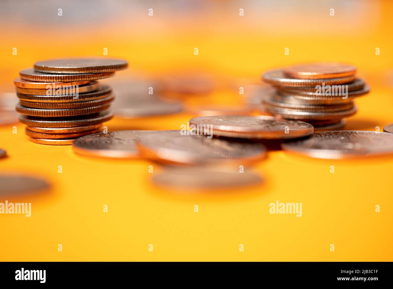 Monete in dollari USA su sfondo arancione. Monete da mezzo dollaro accumulate con penny e quarti. Valuta del dollaro accatastata e accumulata Foto Stock
