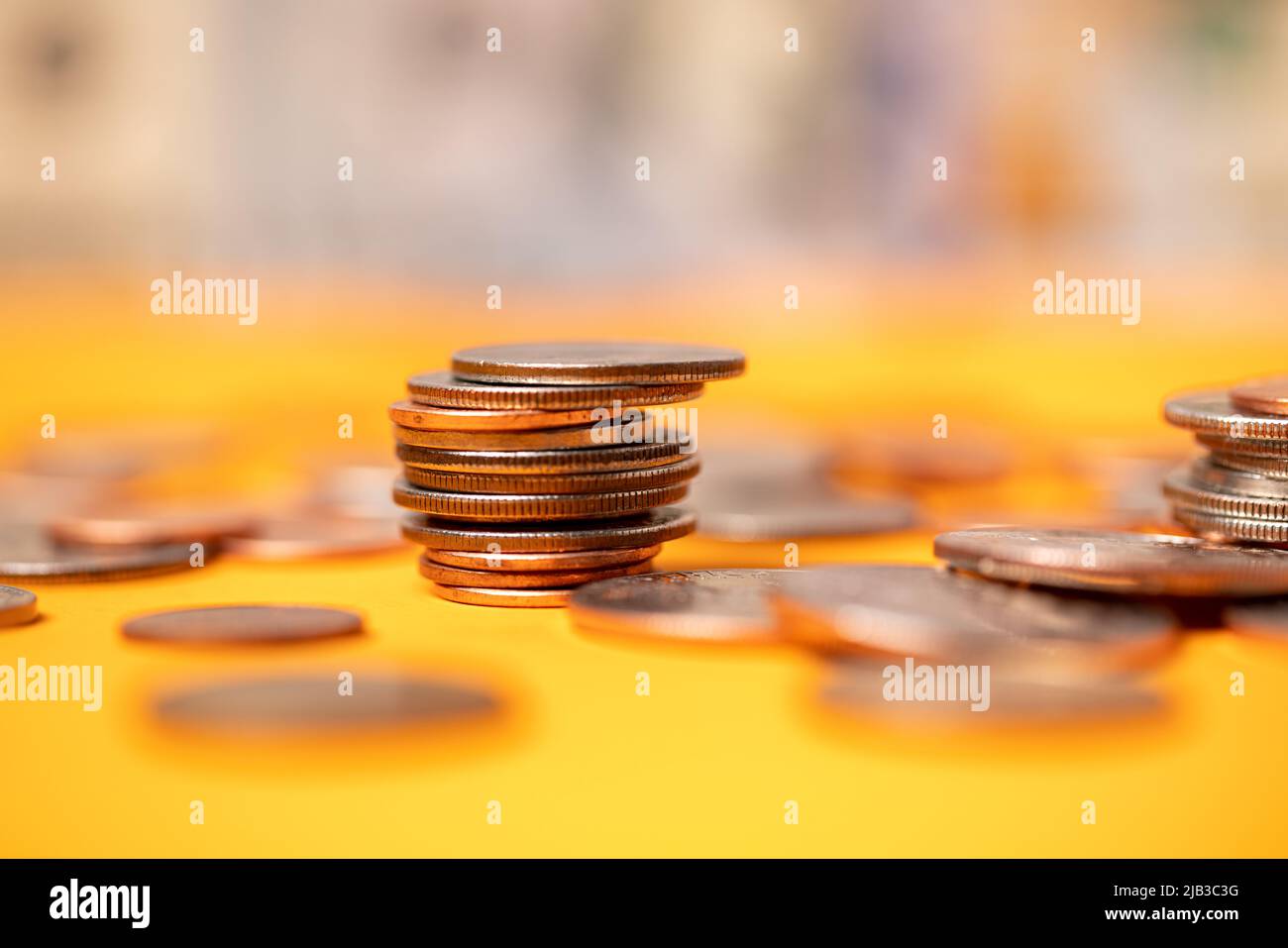 Monete in dollari USA su sfondo arancione. Monete da mezzo dollaro accumulate con penny e quarti. Valuta del dollaro accatastata e accumulata Foto Stock