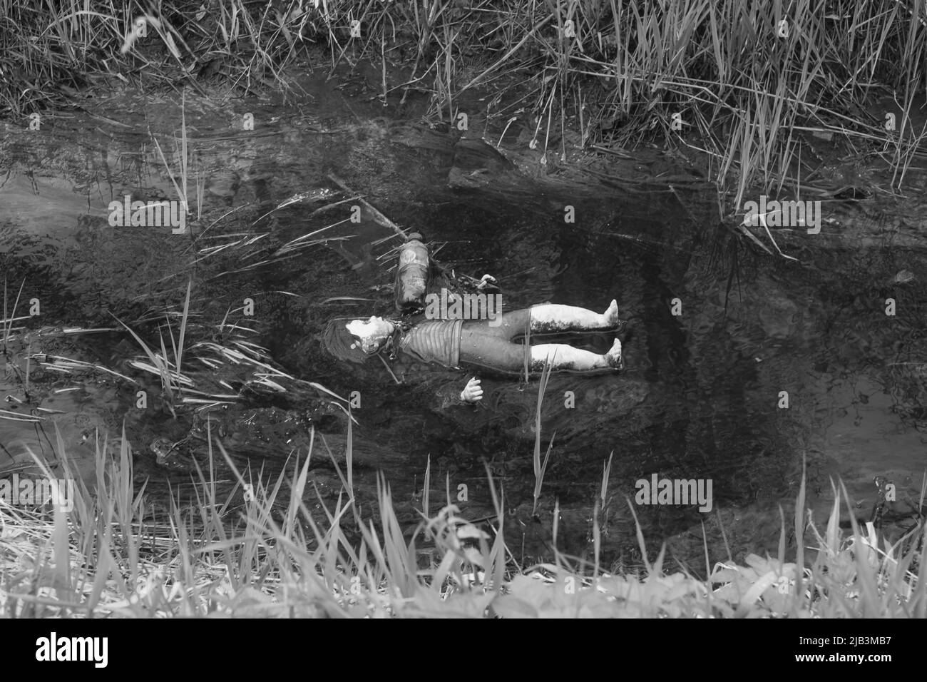 Gettata via vecchia bambola sporca in un fosso fangoso dalla strada. Internazionale perso bambini giorno concetto. Foto Stock