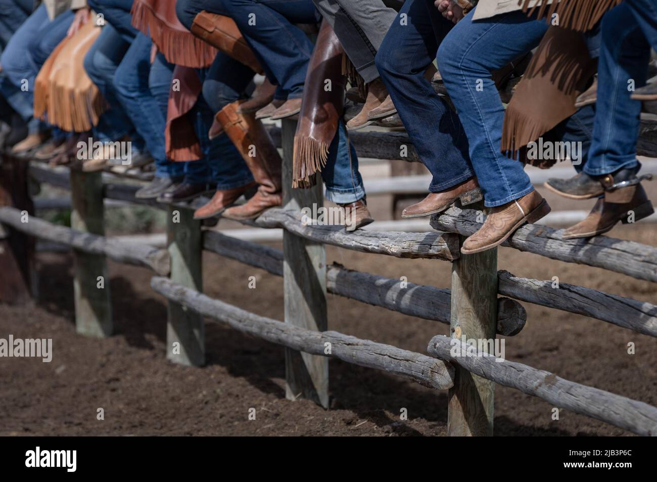 Stivali Cowboy e spur seduti sulla recinzione Corral guardando un rodeo Foto Stock