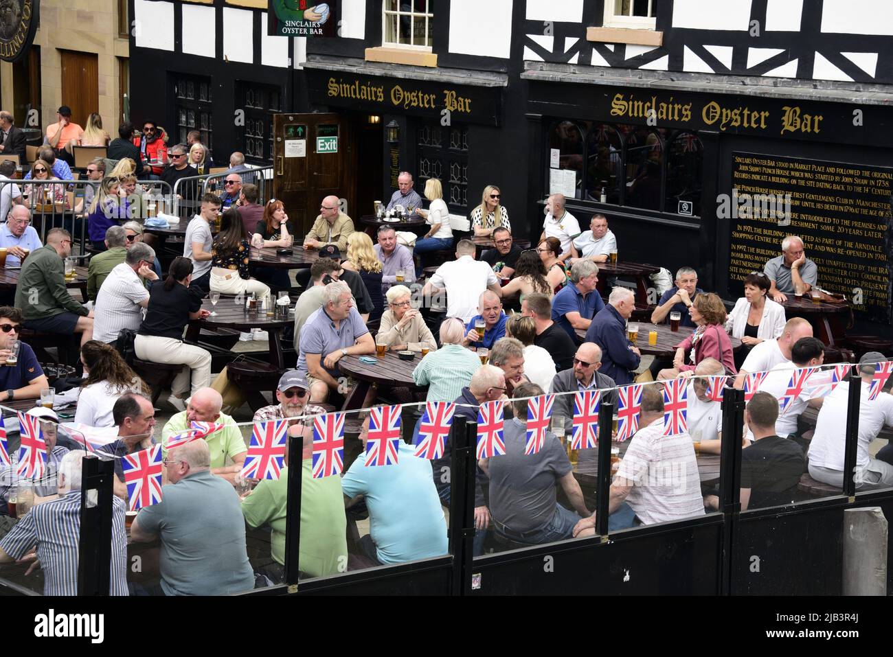 Manchester, Regno Unito, 2nd giugno 2022. La vita quotidiana per le strade del centro di Manchester, Inghilterra, Regno Unito, Isole Britanniche all'inizio del weekend Jubilee Bank Holiday. La gente può gustare un drink all'aperto al Sinclairs Oyster Bar di Exchange Square, con decorazioni a grappolo Union Jack. Credit: Terry Waller/Alamy Live News Foto Stock