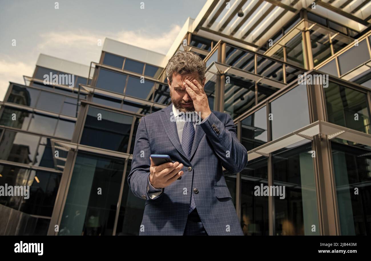 fallimento di uomo d'affari maturo triste in formalwear tenere telefono all'aperto, ansia Foto Stock