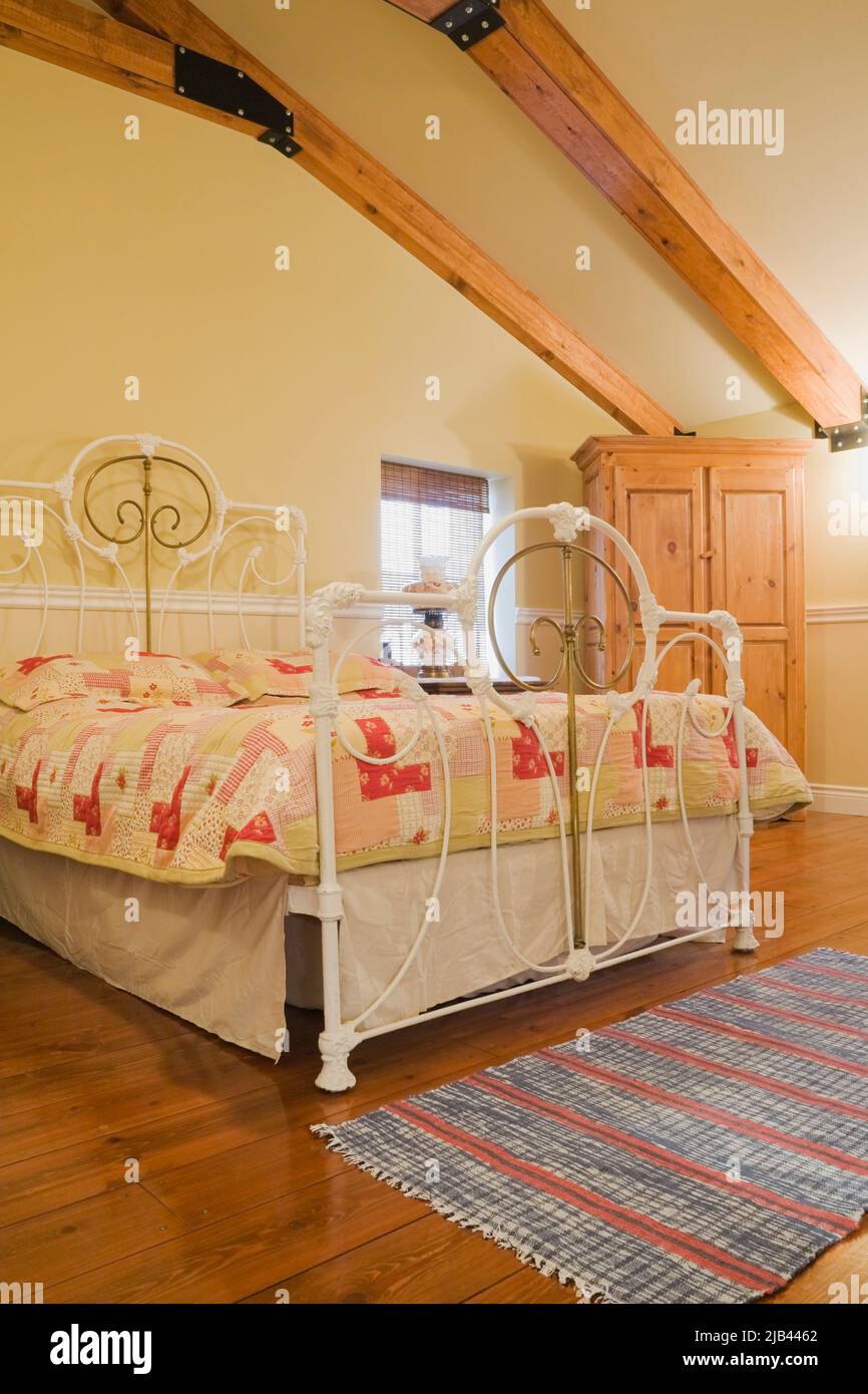 Antico letto queen size con testata in ottone e ferro battuto e pedane in camera da letto all'interno di vecchia casa in mattoni Canadiana stile cottage 1870. Foto Stock
