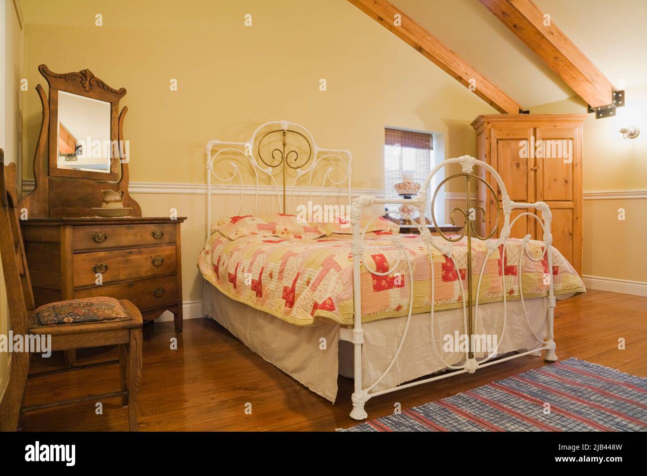 Antico letto queen size con testata e pedane in ottone e ferro battuto, arredamento in camera da letto all'interno della vecchia casa in mattoni Canadiana stile cottage 1870. Foto Stock