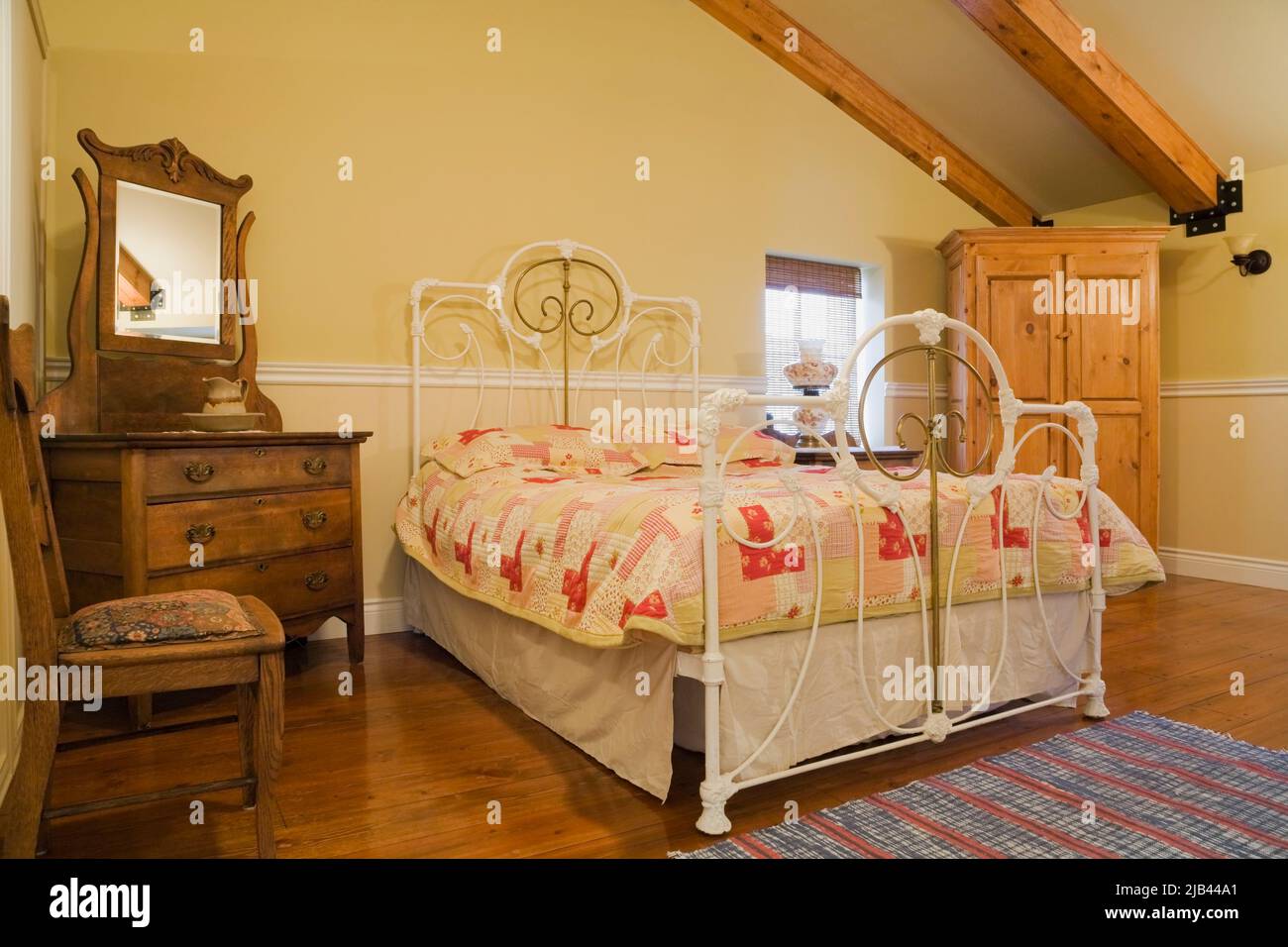 Antico letto queen size con testata e pedane in ottone e ferro battuto, arredamento in camera da letto all'interno della vecchia casa in mattoni Canadiana stile cottage 1870. Foto Stock