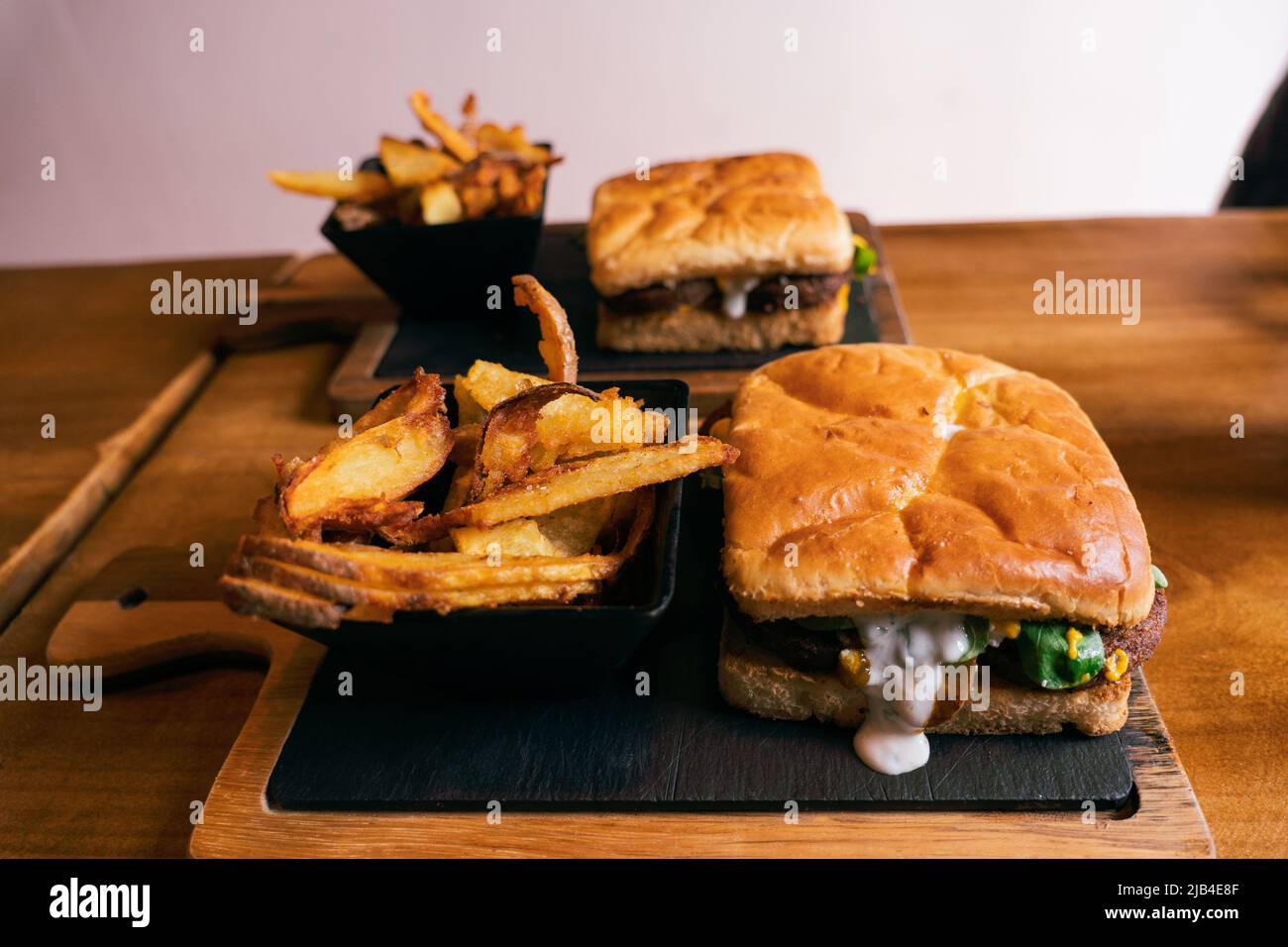 Delizioso panino o hamburger con una porzione di patata dorata patata patata francese su un asse scuro di legno Foto Stock