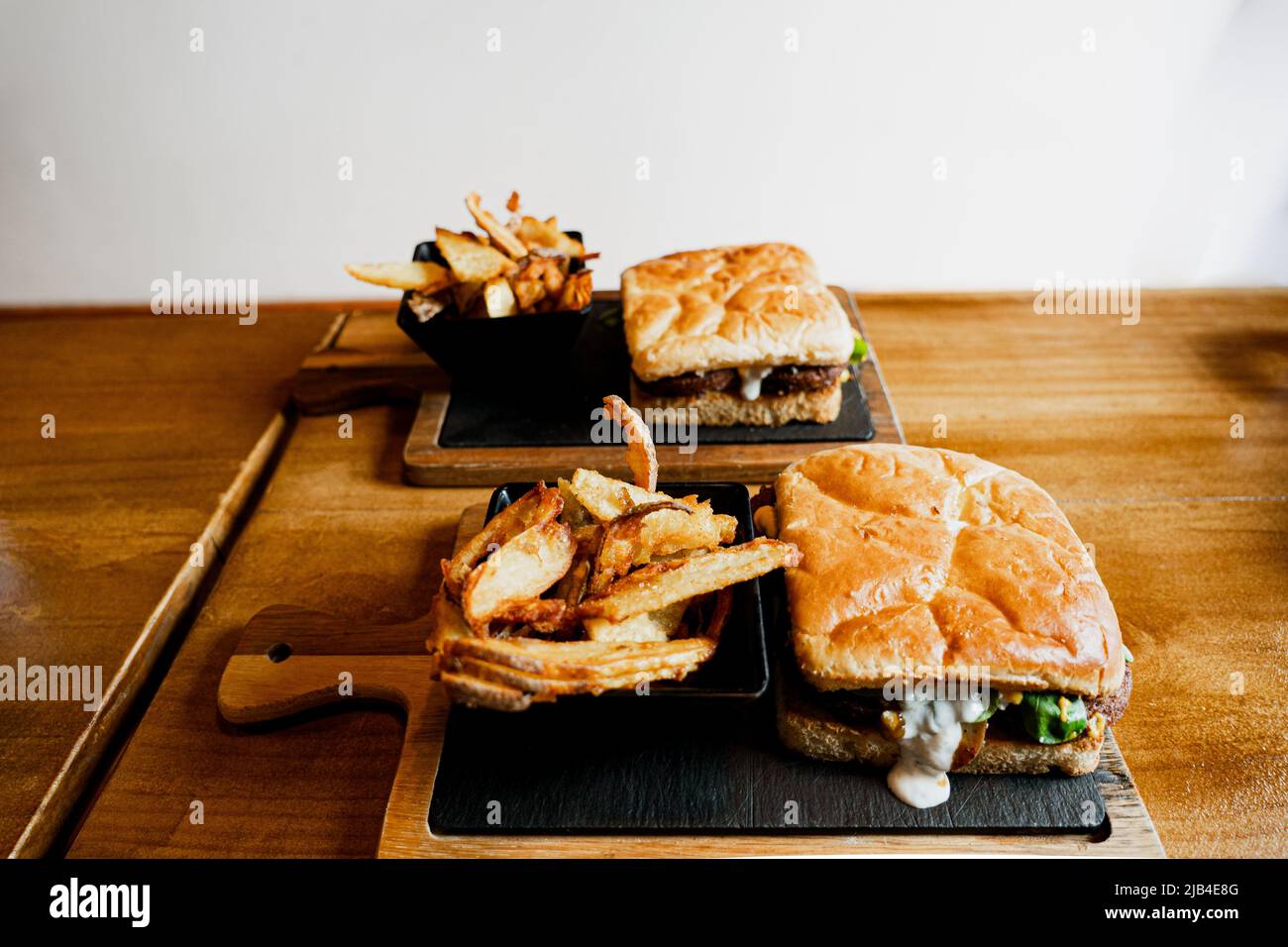 Delizioso panino o hamburger con una porzione di patata dorata patata patata francese su un asse scuro di legno Foto Stock