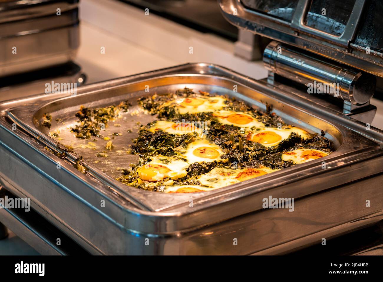 Buffet all-inclusive in vassoi riscaldanti nel ristorante dell'hotel con uova e spinaci per la prima colazione Foto Stock