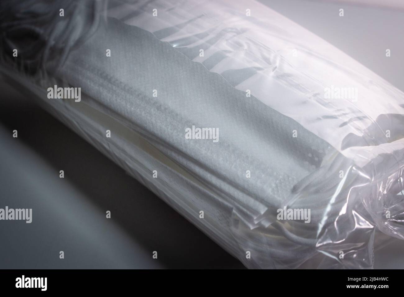 Il set di nuove maschere facciali confezionate in un sottile sacchetto di plastica trasparente su sfondo bianco Foto Stock