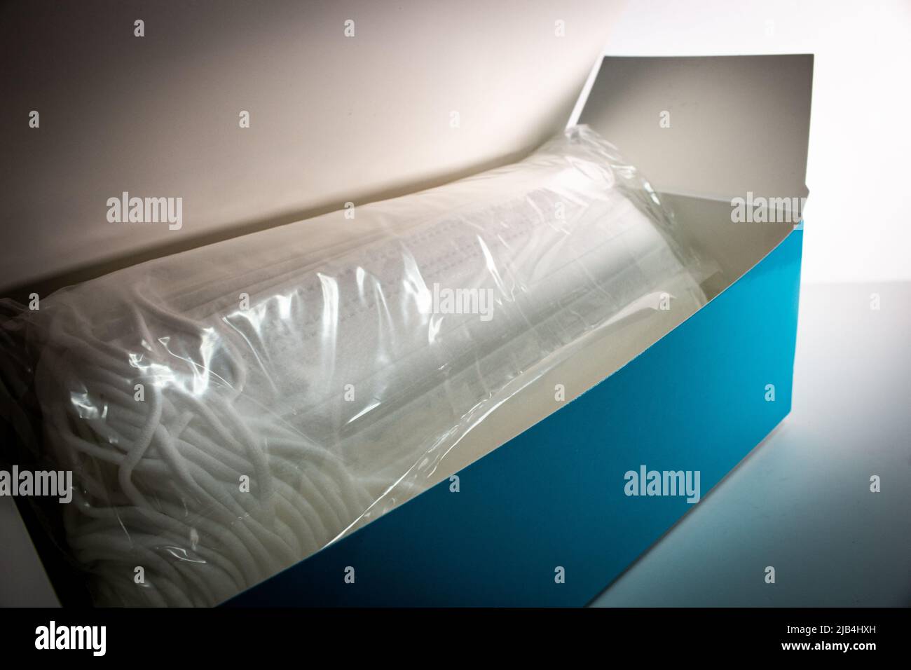 Il set di nuove maschere facciali confezionate in un sottile sacchetto di plastica trasparente nella scatola blu. Foto Stock