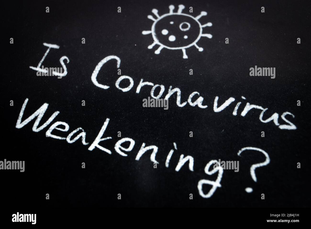Primo piano della frase Coronavirus indebolisce? scrivendo a mano con gesso bianco su lavagna. La superficie della lavagna è polverosa e ruvida. Foto Stock