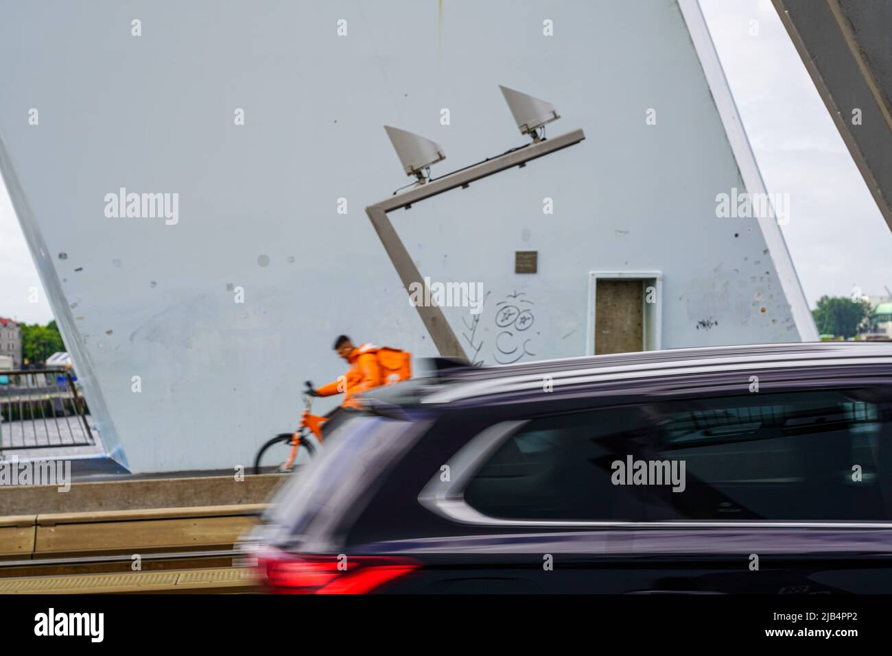 Un'auto e un corriere della bicicletta che si consegnano attraversano il ponte Erasmus in tempo ventoso il 27,2022 maggio a Rotterdam, Paesi Bassi. Foto Stock