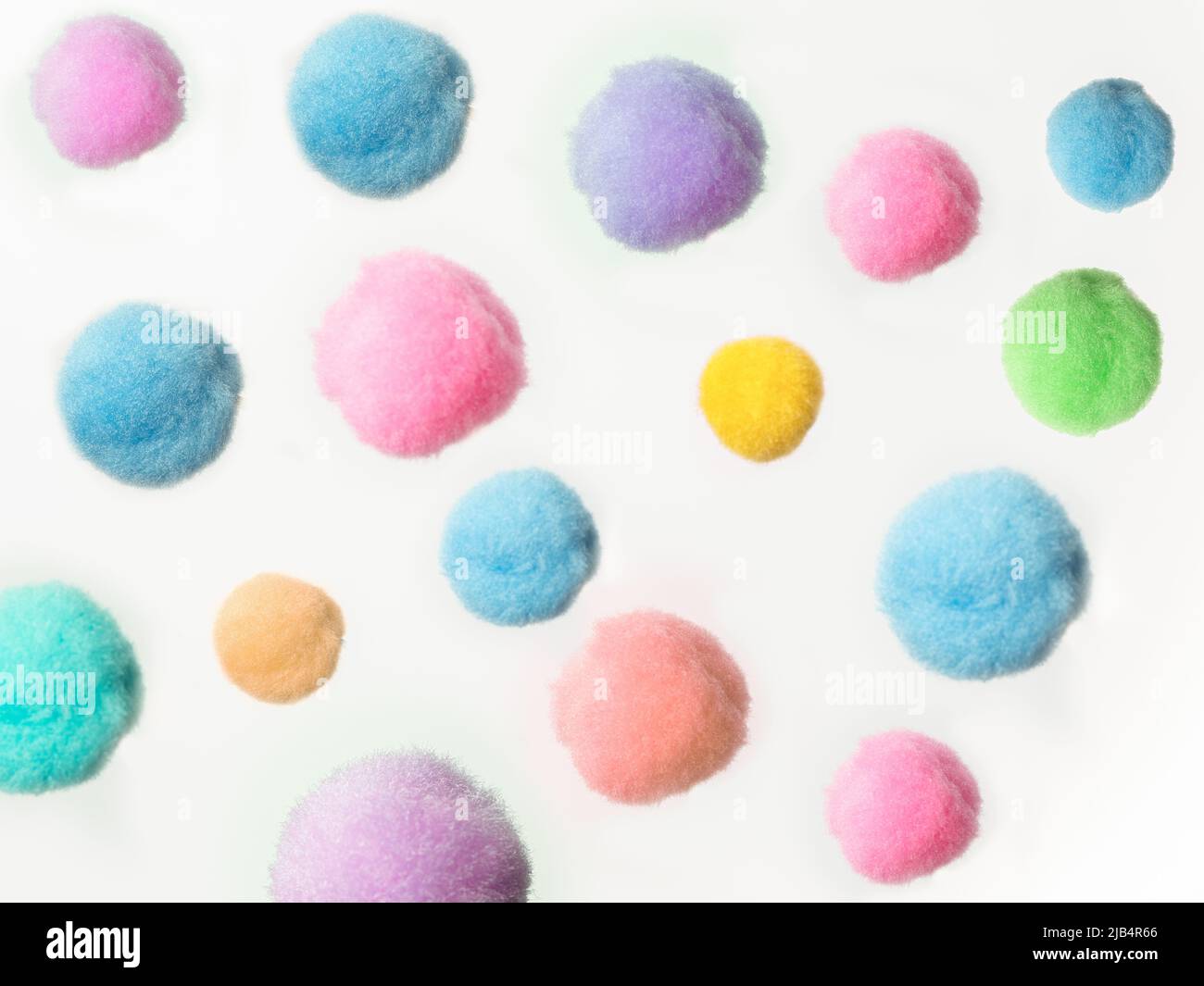 disposizione casuale di palline di pom pom di colore pastello su sfondo bianco Foto Stock