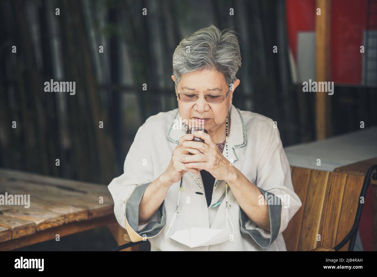 donna anziana anziana asiatica che beve tè caldo in giardino. stile di vita di svago senior Foto Stock