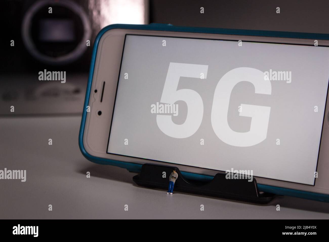 Kumamoto, Giappone - Maggio 21 2020 : 5G sullo schermo dell'iPhone con il giovane ragazzo in miniatura che tocca il suo smartphone su un tavolo bianco in un'atmosfera oscura di notte. Foto Stock