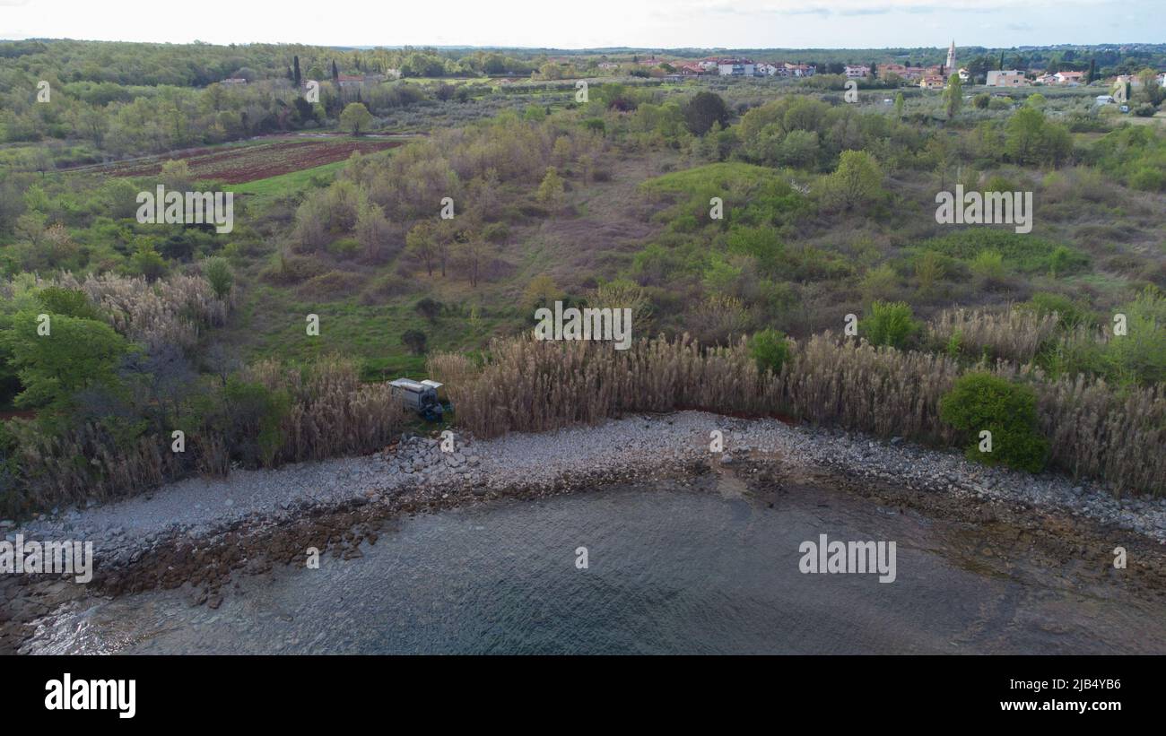 Vista verticale di un furgone o camper parcheggiato proprio accanto al mare o alla spiaggia. Sterrato pista sopra e fresco mare calmo sotto. Foto Stock