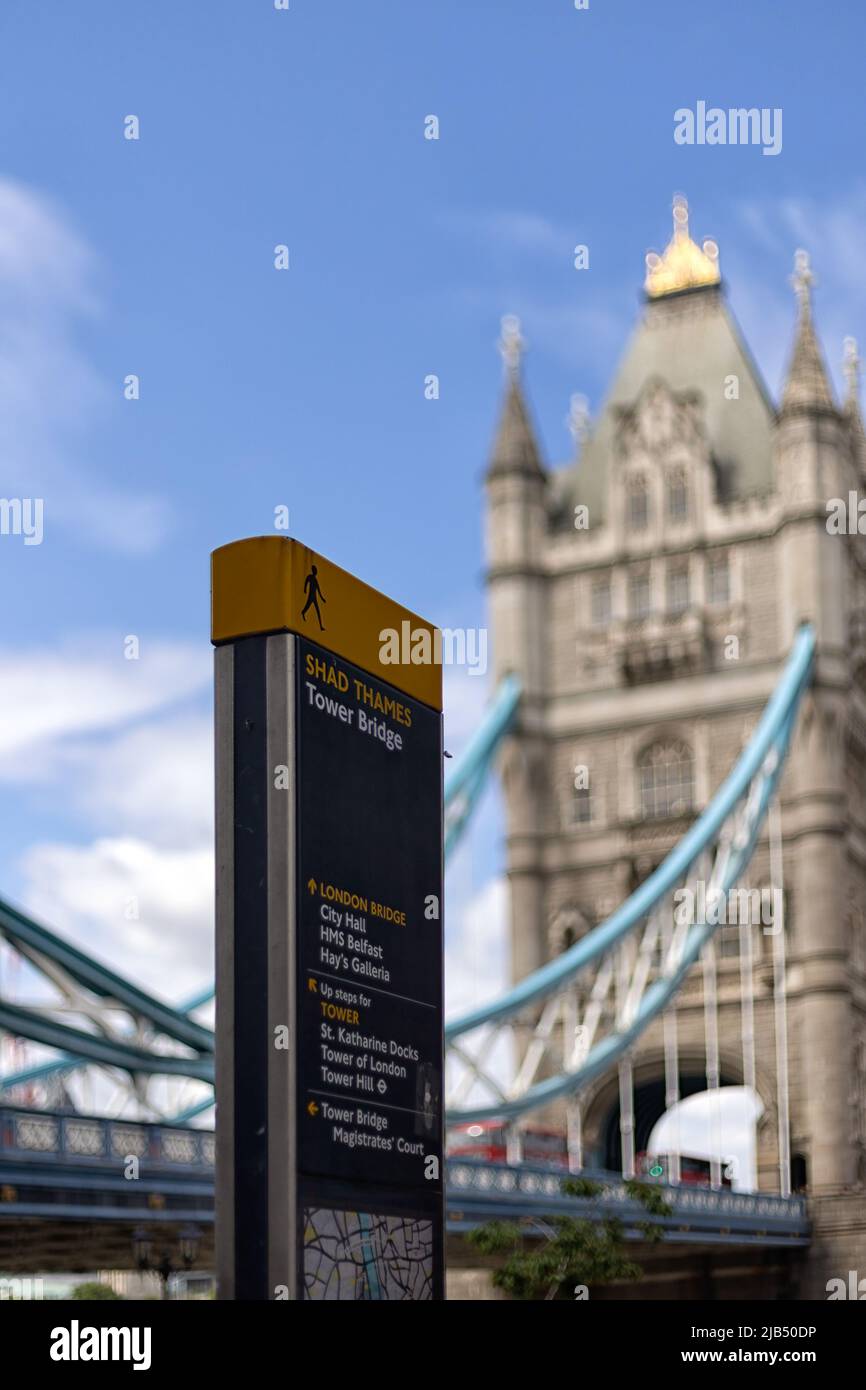 LONDRA, UK - 01 GIUGNO 2022: Ufficio informazioni turistiche con le indicazioni per Tower Bridge e vista sfocata del Tower Bridge sullo sfondo Foto Stock