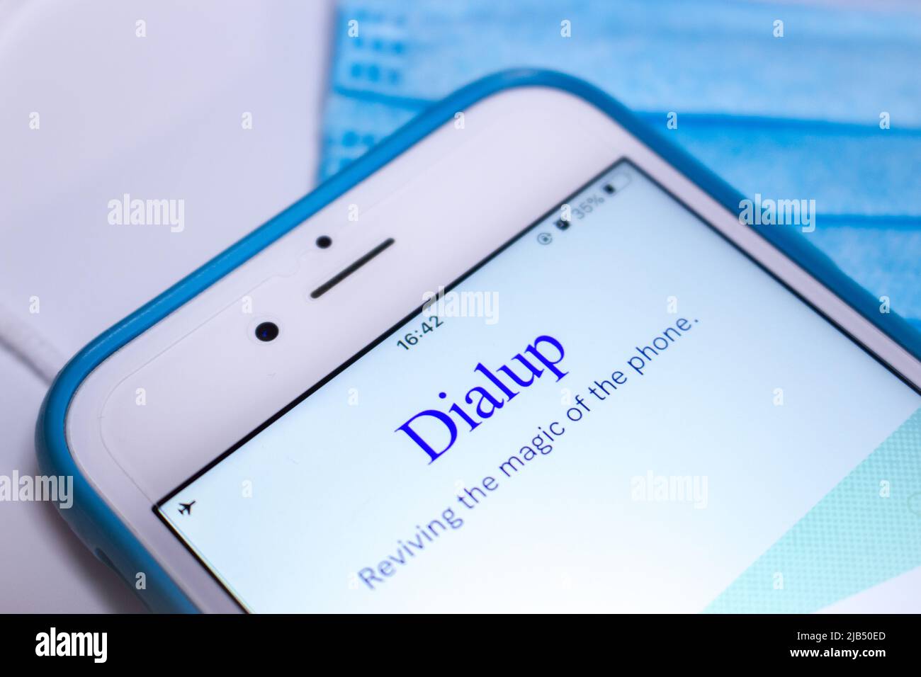 Applicazione Dialup, un'applicazione di chat vocale che connette serendipitamente gli utenti alle persone, su iPhone con maschera medica blu su un tavolo bianco. Foto Stock
