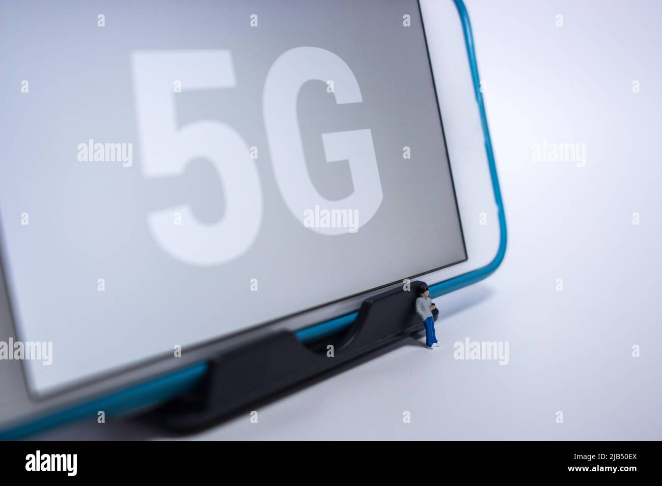 Kumamoto, Giappone - Maggio 21 2020 : il giovane ragazzo in miniatura che tocca il suo smartphone con l'iPhone con 5G sul suo schermo su sfondo bianco. Foto Stock