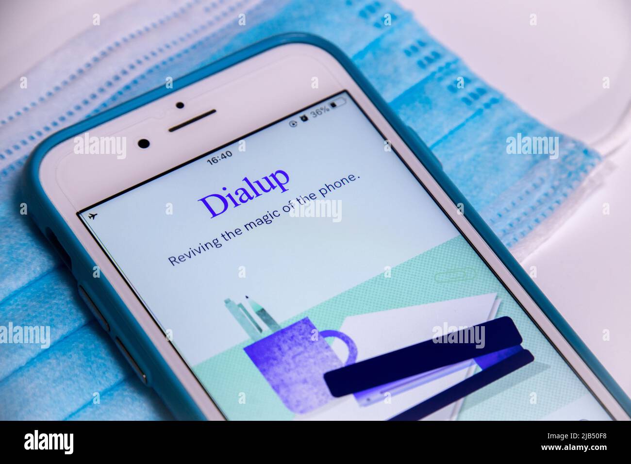 Applicazione Dialup, un'applicazione di chat vocale che connette serendipitamente gli utenti alle persone, su iPhone con maschera medica blu su un tavolo bianco. Foto Stock