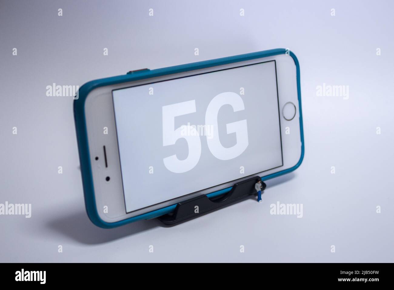 Kumamoto, Giappone - Maggio 21 2020 : 5G sullo schermo dell'iPhone con il giovane ragazzo in miniatura che tocca il suo smartphone su sfondo bianco. Foto Stock