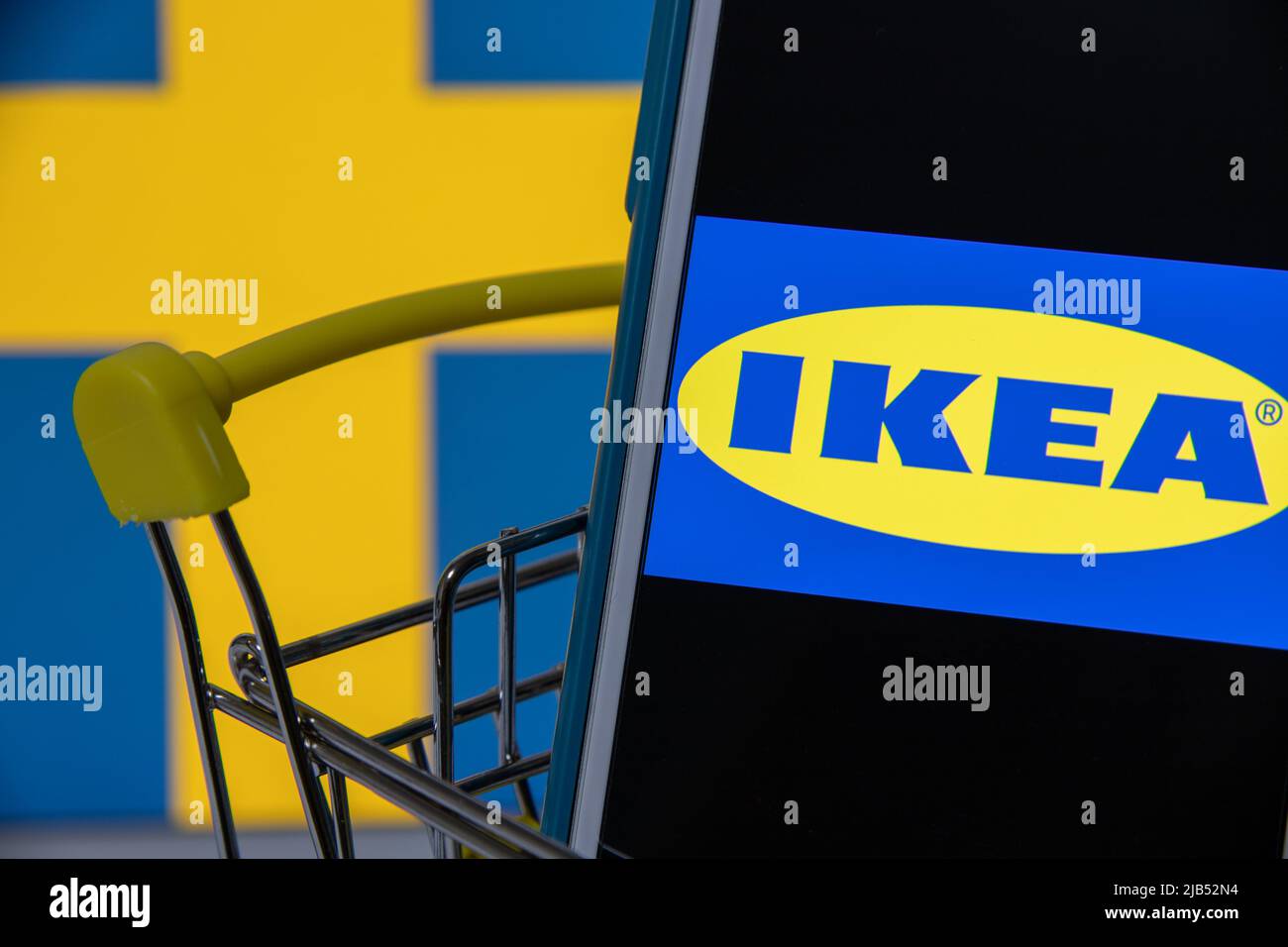 Logo di Ikea, un'azienda svedese che progetta e vende mobili pronti per l'assemblaggio, articoli per la cucina e la casa, su iPhone nel carrello della spesa con bandiera svedese Foto Stock