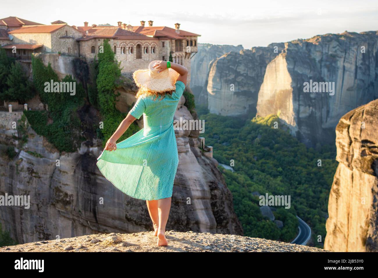 Giovane donna in vestito verde e un cappello che si gode la natura sulle montagne vicino ai monasteri di Meteora. Grecia. Meteora - incredibili formazioni rocciose di arenaria Foto Stock