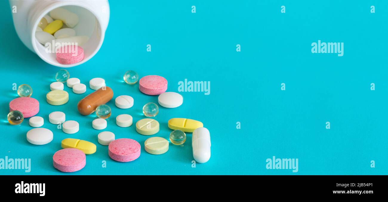 Molte pillole sono versate da una bottiglia di medicina. Pillole e pillole su sfondo blu. Compresse mediche: Analgesici, antipiretici. Foto Stock