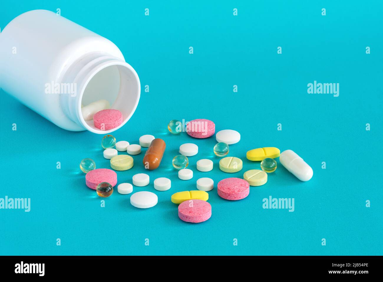 Molte pillole sono versate da una bottiglia di medicina. Pillole e pillole su sfondo blu. Compresse mediche: Analgesici, antipiretici. Foto Stock