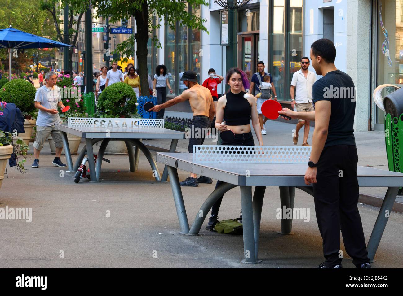 La gente gioca a ping pong in Plaza 33 spazio pubblico vicino a Herald Square a New York, NY, 30 maggio 2022. Cornilleau Park tavoli da ping pong all'aperto. Foto Stock