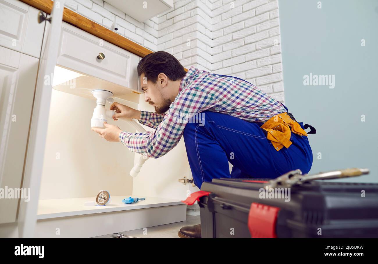 Idraulico che fissa alcuni problemi con il lavello della cucina, riparando i tubi o disintasando il blocco Foto Stock