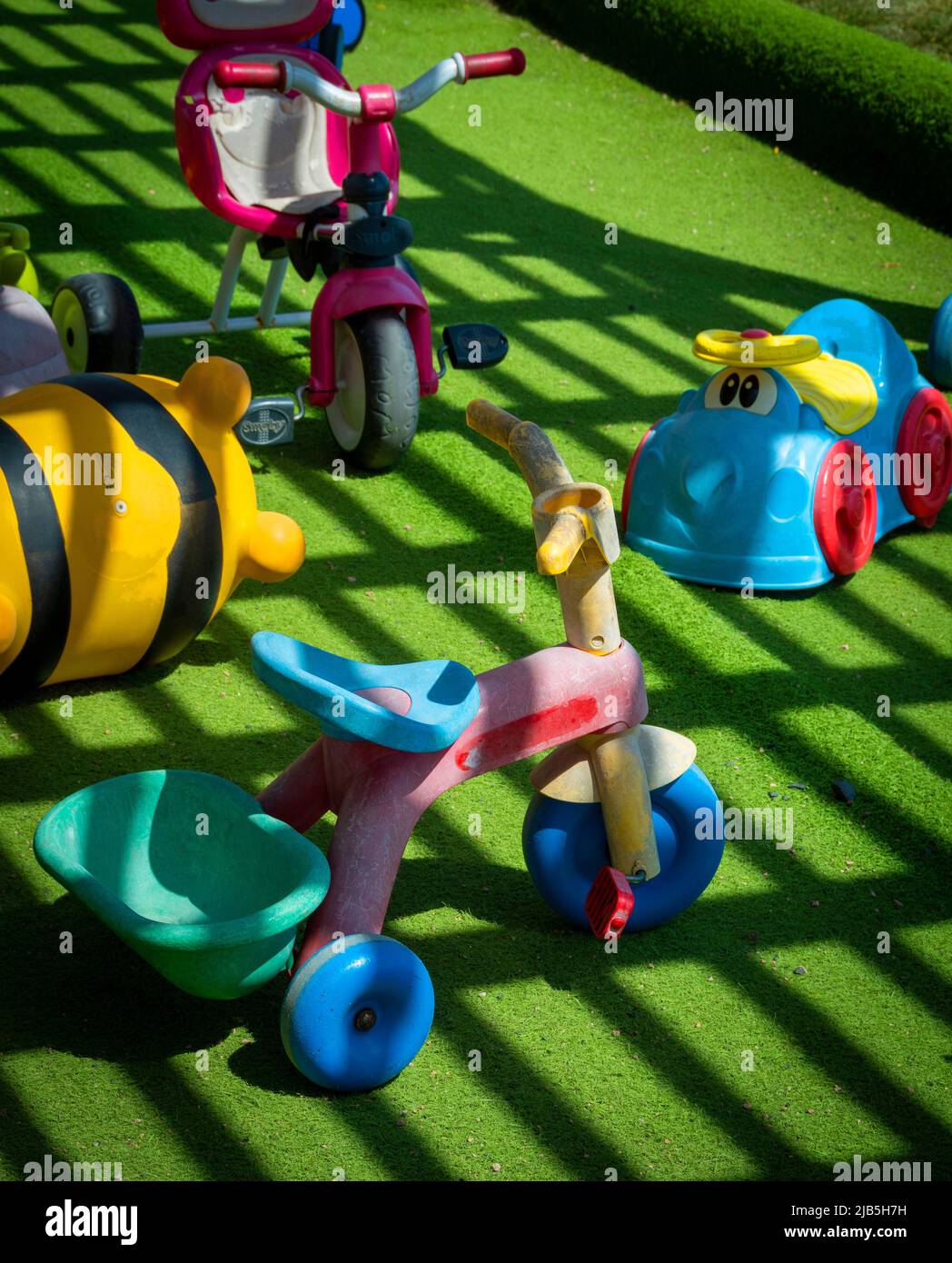 I coloratissimi giocattoli per bambini sparsi su una vibrante erba verde in un divertente ambiente all'aperto Foto Stock