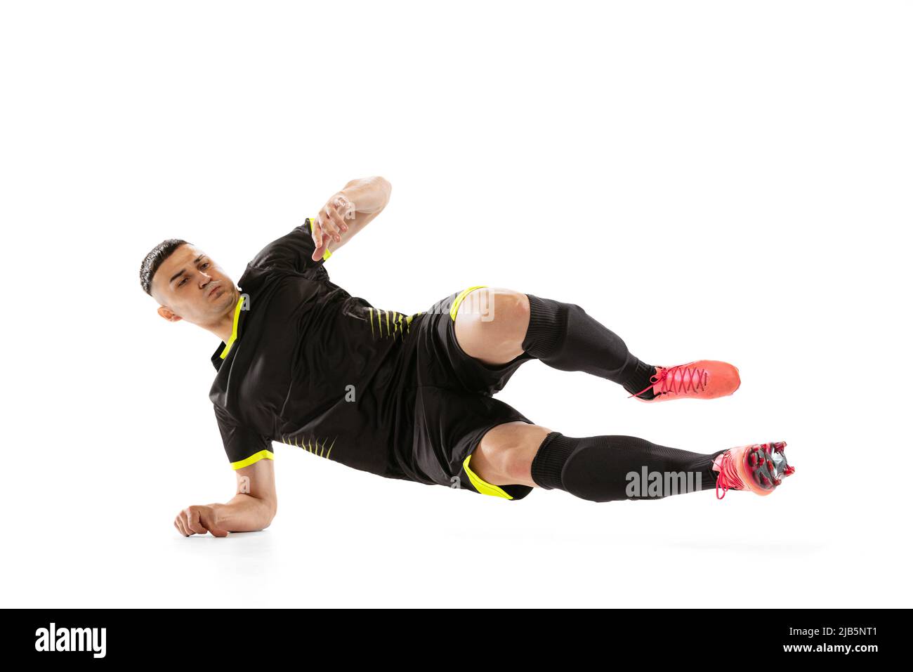 Un giocatore professionista di calcio maschile che fa sliding tackle isolato su sfondo bianco studio. Concetto di sport, obiettivi, competizione, hobby Foto Stock