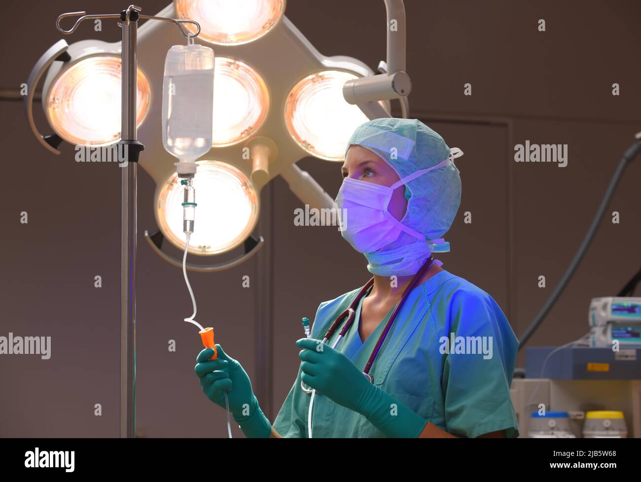 In una sala operatoria è presente un infermiere anestetico. Si vede vestita di abbigliamento medico sterile verde con una maschera sul viso. Foto Stock