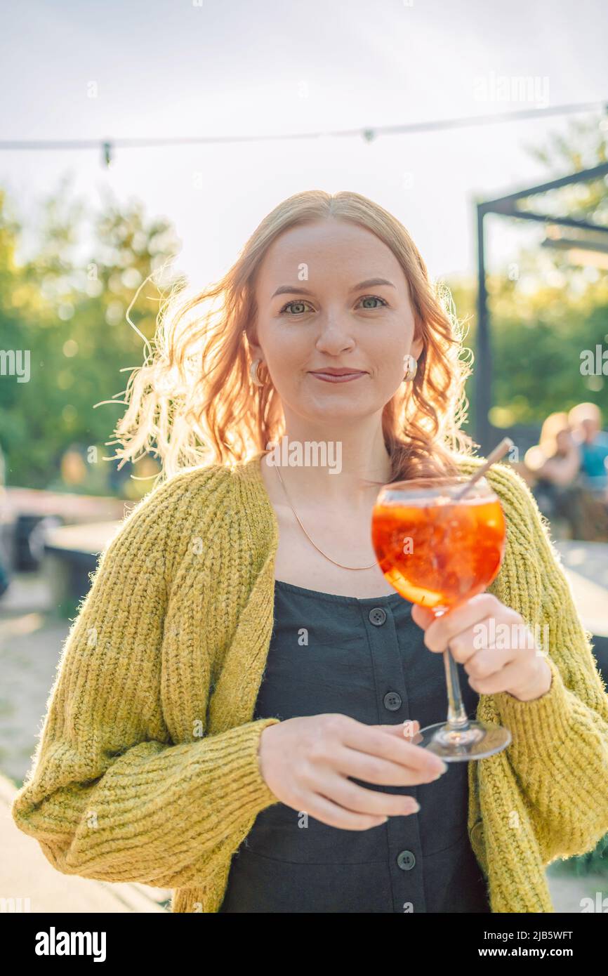 Bella europea 30s ragazza che si diverte in caffè e bere cocktail di frutta con piacere, vestito fresco al ristorante nel fine settimana Foto Stock