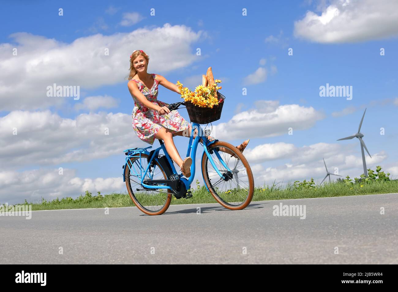Una giovane donna spensierata ama la sua nuova bicicletta elettrica ibrida. Si prende per un giro rilassante nel paese senza usare i pedali della bicicletta. Foto Stock