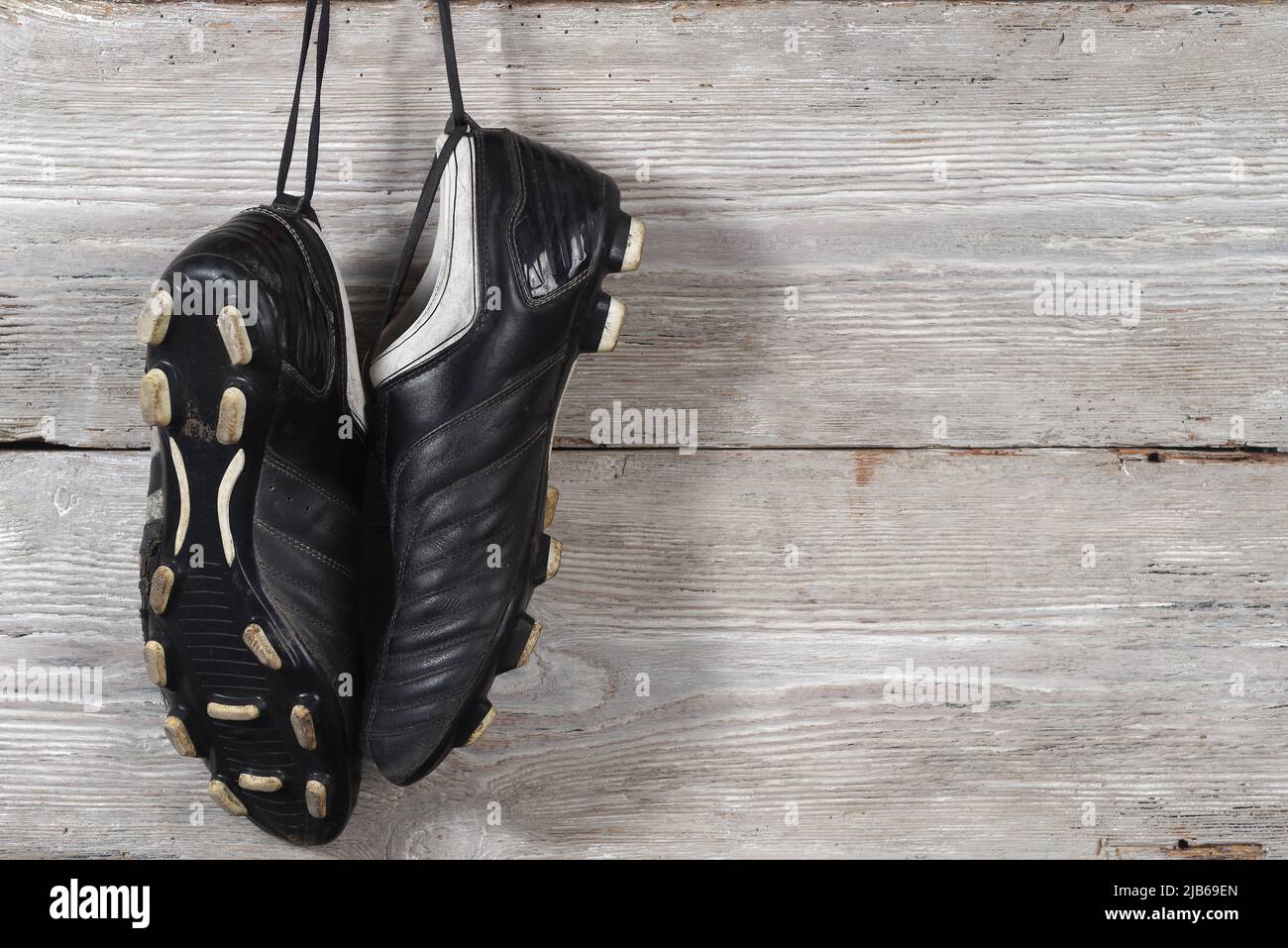 Un paio di stivali da calcio appesi su un muro di legno. La fine della carriera calcistica Foto Stock
