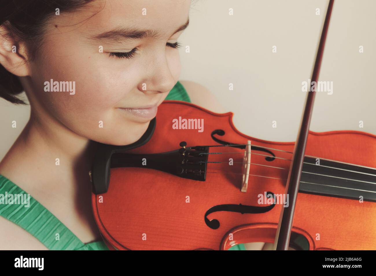 Bambina che gioca un violino, espressione facciale. Foto Stock